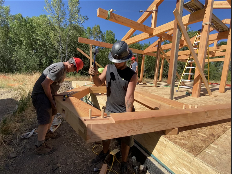 Hammering Pegs at a timber frame raising in Oregon